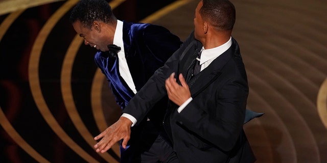 Will Smith, right, punches presenter Chris Rock onstage while presenting the award for Best Documentary Feature at the Oscars on March 27, 2022, at the Dolby Theater in Los Angeles.