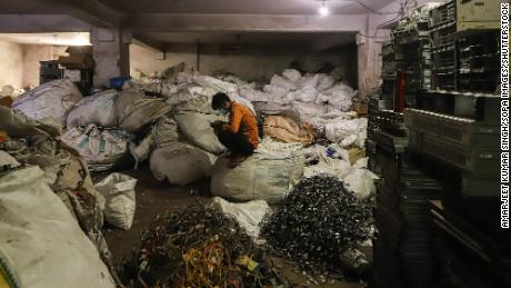 A man sits in front of e-waste or computer e-waste at a workshop in New Delhi, India in July 2020.