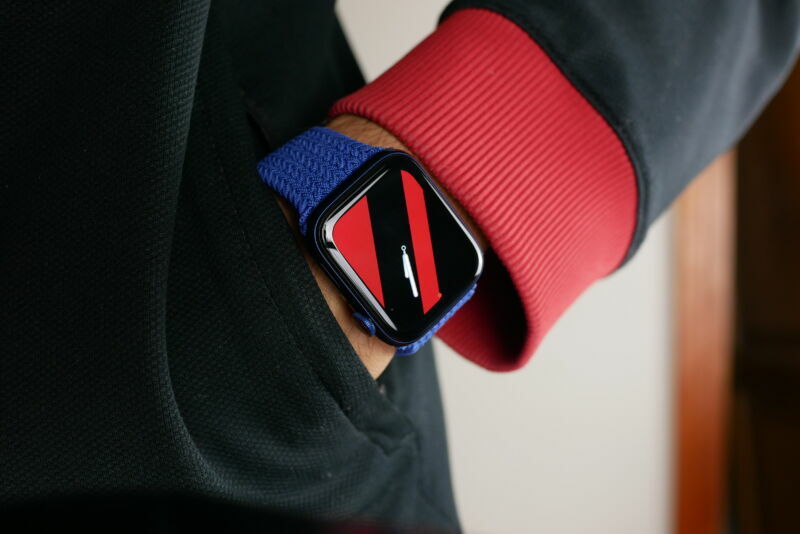 Extreme close up photograph of a wristwatch on a hand in a trouser pocket.