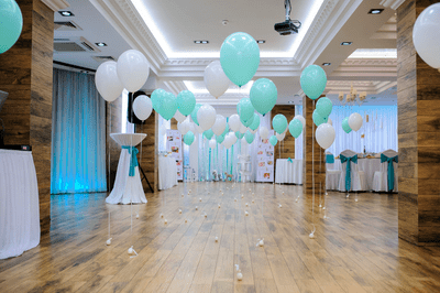 A large empty room decorated for a party with balloons and ribbons but no one visible