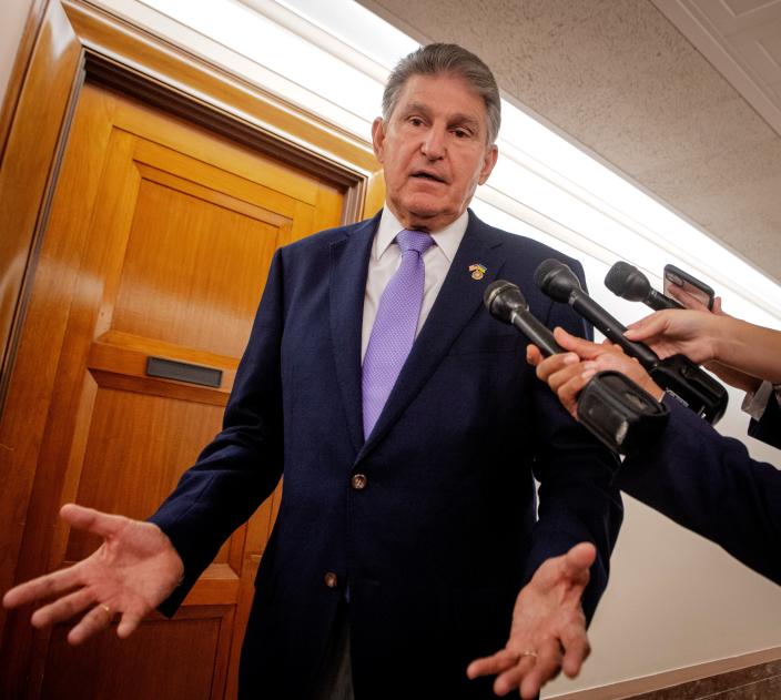 An image of Senator Joe Manchin on Capitol Hill, with three microphones pointed at him.